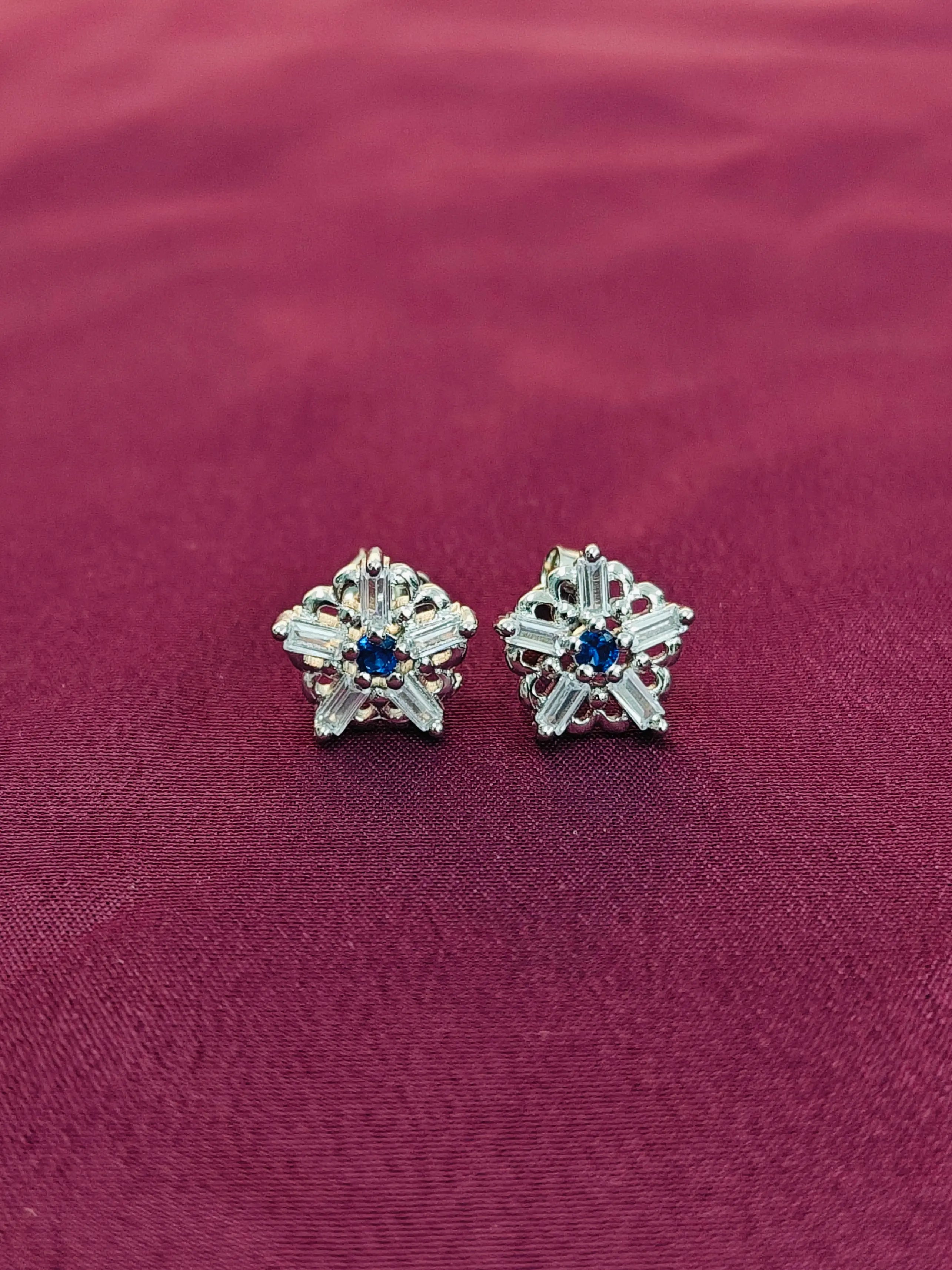 Star-shaped earrings with gemstones on a red fabric background